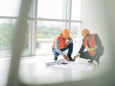 Civil engineers discussing blueprint on the floor